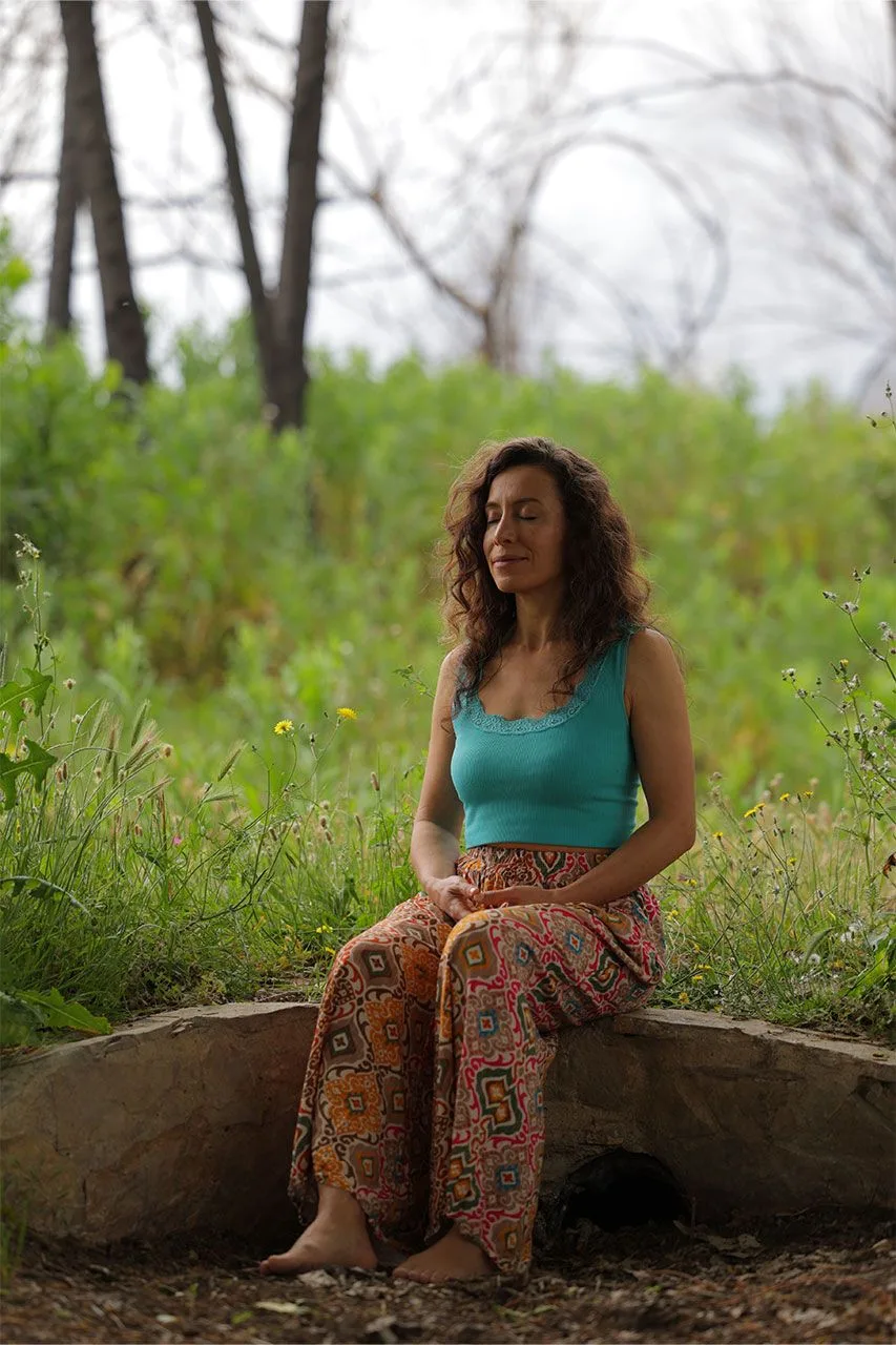 Sara Tau sentada en la naturaleza, en una práctica de escucha corporal